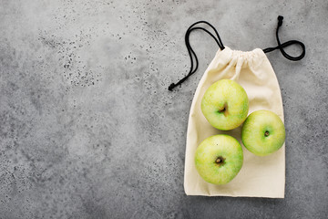 Eco bag for products. Apples on the background of a linen bag on a light gray background. Copy space