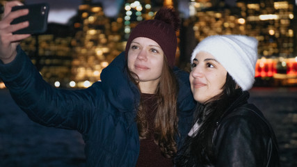 Two girls enjoy a wonderful night in New York in front of the Manhattan skyline