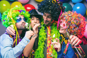Lachende Freunde in bunten Kostümen trinken Sekt bei einer Karneval party .