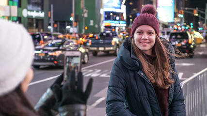 Fototapeta na wymiar Two girls in New York take photos at Times Square