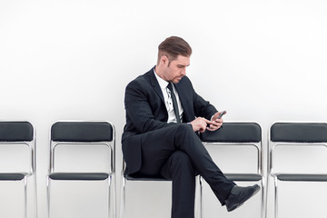 businessman with mobile sitting in the office hallway