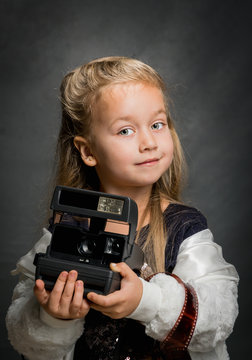 Little beautiful girl with an old camera. Young photographer