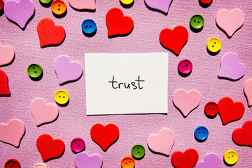 Trust - word on pink background with hearts decorations, religion or business concept