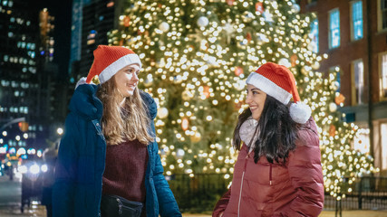 Two girls in front of a Christmas tree enjoy the wonderful time in New York