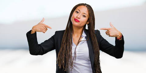 Portrait of a young black business woman proud and confident, pointing fingers, example to follow,...