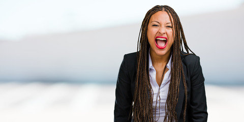 Portrait of a young black business woman screaming angry, expression of madness and mental...
