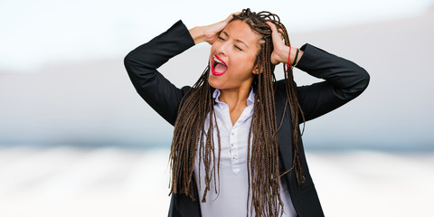 Portrait of a young black business woman crazy and desperate, screaming out of control, funny...