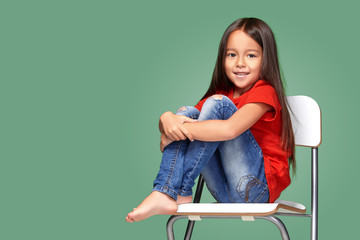 little girl wearing red t-short and posing on chair