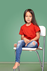 little girl wearing red t-short and posing on chair