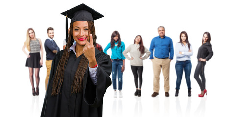 Young graduated black woman wearing braids showing number one, symbol of counting, concept of mathematics, confident and cheerful