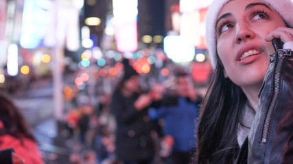 Young woman takes a phone call on Times Square by night