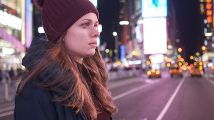 Beautiful girl walks through the city of New York at Times Square by night