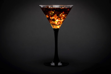 Glass of whiskey with ice or brandy isolated on a black background. Whiskey with ice in the glass on a black background.