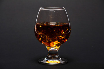 Glass of whiskey with ice or brandy isolated on a black background. Whiskey with ice in the glass on a black background.