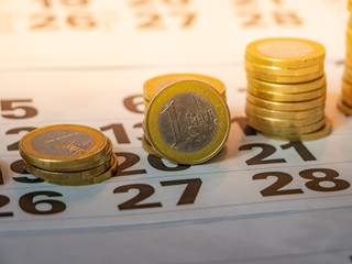 Image of Euro coin stacks on calender indicating pay day