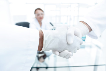 Doctors in lab coats greeting each other with handshake