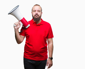 Young caucasian man shoutithrough megaphone over isolated background with a confident expression on smart face thinking serious