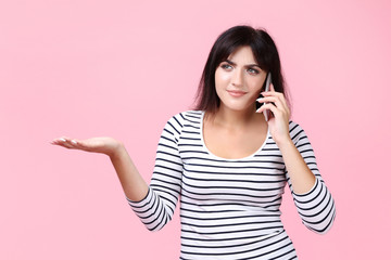 Young woman with smartphone on pink background