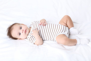 Obraz na płótnie Canvas Cute baby lying on white bed