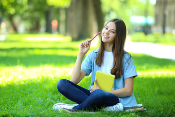 Cute girl sitting with book in the park