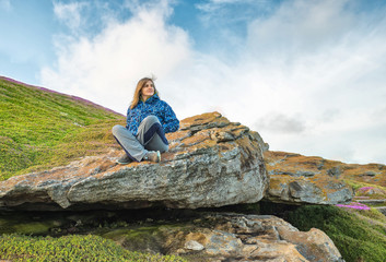 Naklejka premium woman sitting stones against the sky