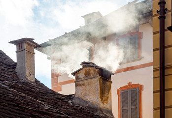 Smoke raising from a house chimney directly in front of  windows, air pollution 