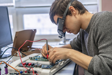 young man in special zoom glasses work with silicon electronic chip b
