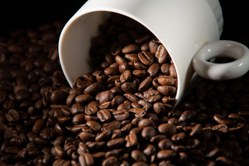 white cups with a pattern and grains of coffee on a black background