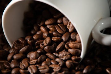 white cups with a pattern and grains of coffee on a black background