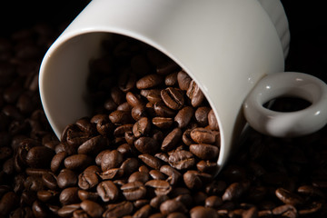 white cups with a pattern and grains of coffee on a black background