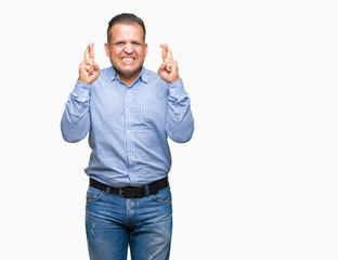 Fototapeta premium Middle age arab business man over isolated background smiling crossing fingers with hope and eyes closed. Luck and superstitious concept.