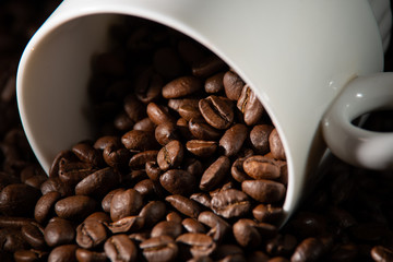 white cups with a pattern and grains of coffee on a black background