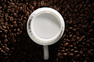 white cups with a pattern and grains of coffee on a black background