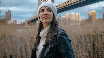 Young woman walks along Hudson River at Brooklyn Bridge New York
