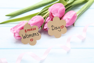 Text 8 March Women's Day with pink tulip flowers and ribbon on wooden table