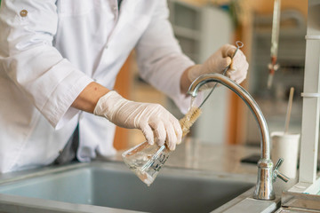 scientist wash beaker from poisonous acid after experiments b