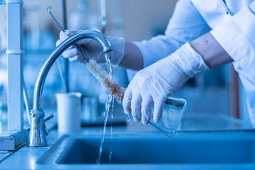 scientist wash beaker from poisonous acid after experiments b