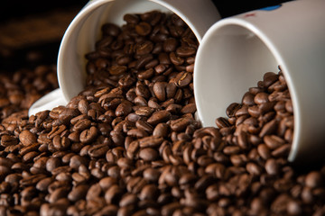 white cups with a pattern and grains of coffee on a black background