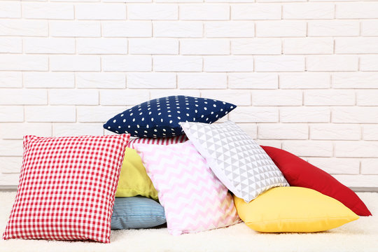 Soft colorful pillows on brick wall background