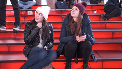 Two girls at Times Square by night sit on the famous red steps