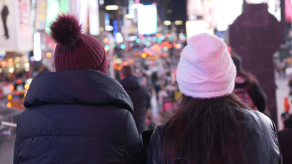 Two girls in New York enjoy the amazing view over Times Square by night