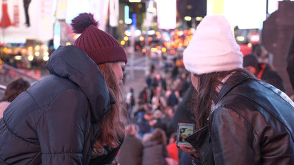 Two girls in New York enjoy the amazing view over Times Square by night