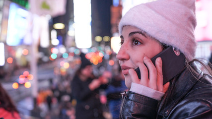 Young woman takes a phone call on Times Square by night