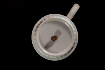 white cups with a pattern and grains of coffee on a black background