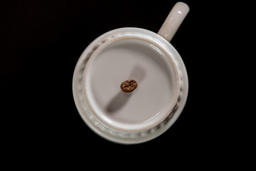 white cups with a pattern and grains of coffee on a black background