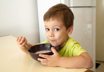 The little boy eats porridge oatmeal