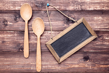 Wooden kitchen spoons with blank frame on brown table