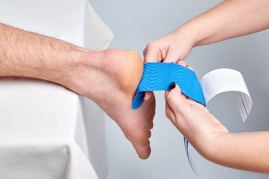 doctor physiotherapist hands applying kinesio medical taping on the ankle