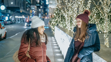 Two girls in New York at Christmas time enjoy shopping presents