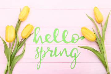 Bouquet of yellow tulips with text Hello Spring on wooden table